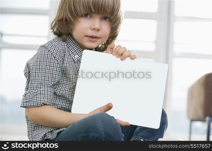 Portrait of cute boy showing his drawing on digital tablet at home