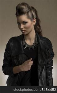 portrait of cute brunette girl with long wavy hair and fashion casual style. wearing leather jacket and rock necklace