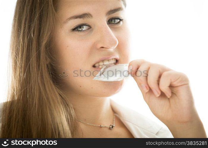 Portrait of cute brunette woman holding condom in mouth
