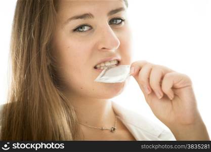 Portrait of cute brunette woman holding condom in mouth