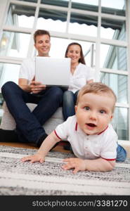 Portrait of cute child with parents using laptop in the background