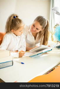 Portrait of cute daughter doing homework with mother