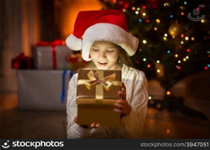 Portrait of cute excited girl looking in magic Christmas box at night
