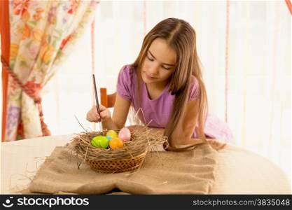 Portrait of cute girl decorating easter eggs in basket
