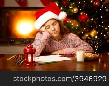 Portrait of cute girl fell asleep while writing letter to Santa