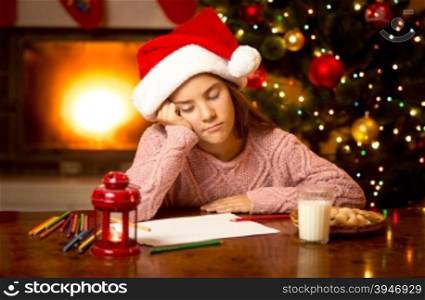 Portrait of cute girl fell asleep while writing letter to Santa