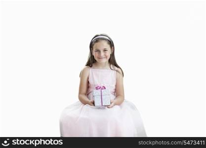 Portrait of cute girl holding gift box over white background