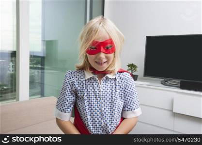 Portrait of cute girl in super hero costume at home