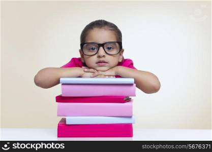 Portrait of cute girl leaning on stack of books against colored background