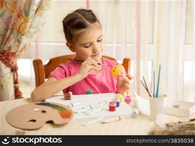 Portrait of cute girl painting Easter egg at home
