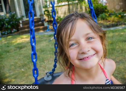 Portrait of cute girl playing on swing in garden