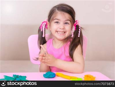 Portrait of Cute girl playing with toys for playdough near table. Selective focus and small depth of field.. Portrait of Cute girl playing with toys for playdough