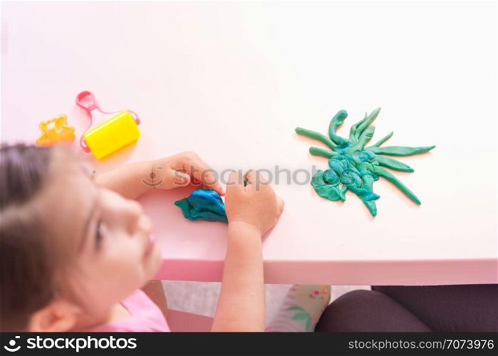 Portrait of Cute girl playing with toys for playdough near table. Selective focus and small depth of field.. Portrait of Cute girl playing with toys for playdough
