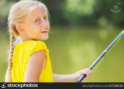 Portrait of cute girl sitting at bank and fishing