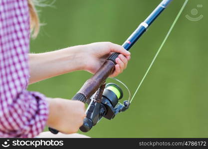 Portrait of cute girl sitting at bank and fishing