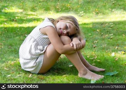 Portrait of cute girl sitting on green grass