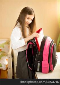 Portrait of cute girl taking things out of her school bag