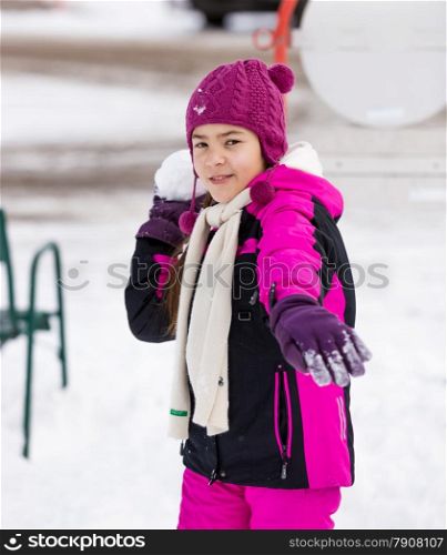 Portrait of cute girl throwing snowball at camera