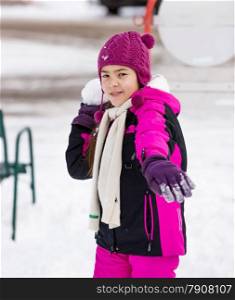 Portrait of cute girl throwing snowball at camera