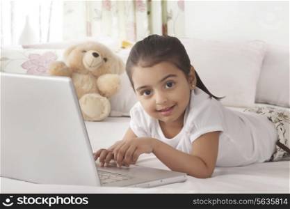 Portrait of cute girl using laptop in bed