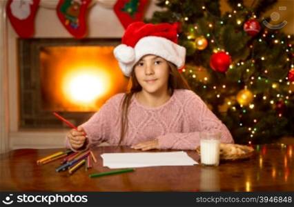 Portrait of cute girl waiting for Santa with milk and cookies at living room
