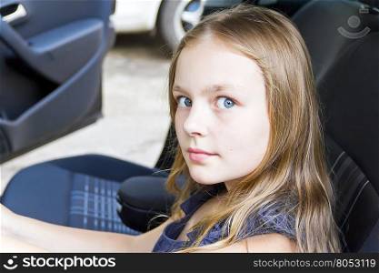 Portrait of cute girl with blond hair sitting in the car