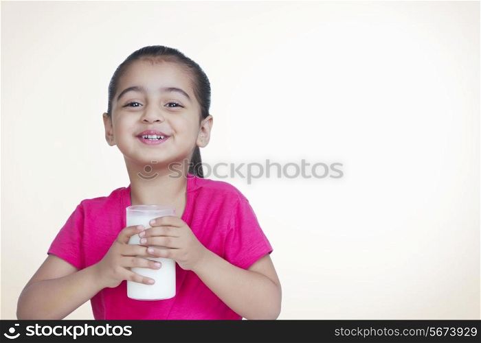 Portrait of cute girl with glass of milk against colored background