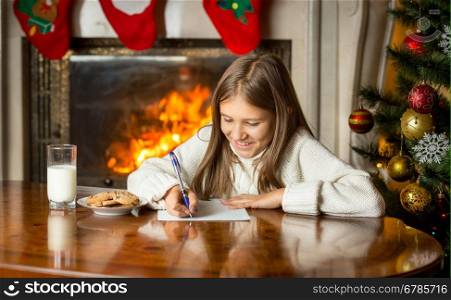 Portrait of cute girl writing letter to Santa Claus at Christmas eve