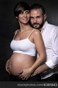 Portrait of cute happy couple expecting baby over black background, enjoying pregnancy and each other, love and happiness concept