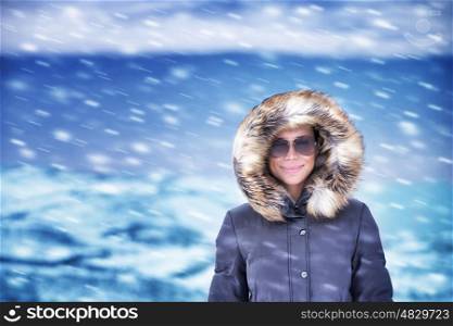 Portrait of cute happy woman on vacation, having fun outdoors enjoying snowfall, wearing stylish warm coat with fur on hood, winter fashion concept