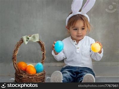 Portrait of Cute Little Baby Boy with Basket Full of Colorful Eggs. Egg Hunting. Bunny Ears. Happy Easter Holiday.. Happy Baby Boy with Easter Eggs