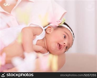Portrait of cute little baby girl on mothers hands, young happy family spending time at home, tenderness and love concept