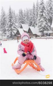 portrait of cute little girl child sitting on sledges at winter day with fresh snow, eat cookies and have break