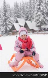 portrait of cute little girl child sitting on sledges at winter day with fresh snow, eat cookies and have break