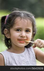 Portrait of cute little girl holding candy stick