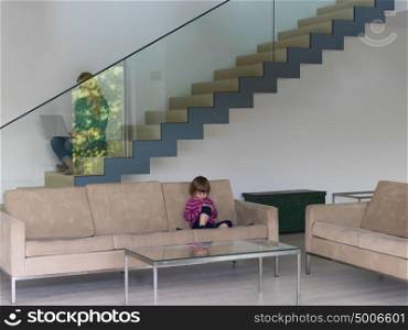 Portrait of cute little girl playing games on smartphone at home