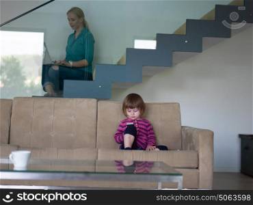 Portrait of cute little girl playing games on smartphone at home
