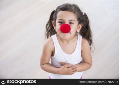 Portrait of cute little girl wearing clown nose at home