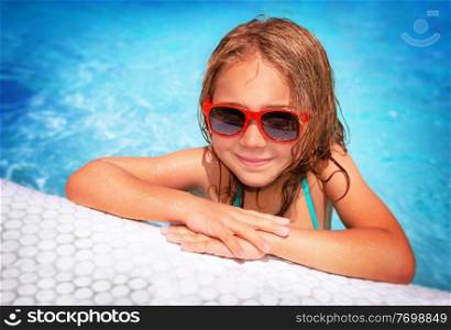 Portrait of cute little girl wearing sunglasses having fun in swimming pool, spending summer vacation on the beach resort