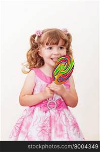 Portrait of cute little girl with big colorful lollipop on a light background