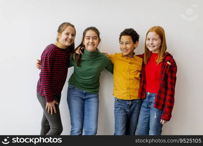 Portrait of cute little kids in jeans  looking at camera and smiling, standing against the white wall