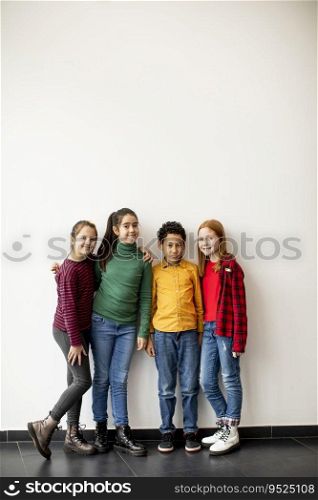 Portrait of cute little kids in jeans  looking at camera and smiling, standing against the white wall