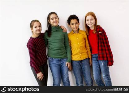 Portrait of cute little kids in jeans  looking at camera and smiling, standing against the white wall