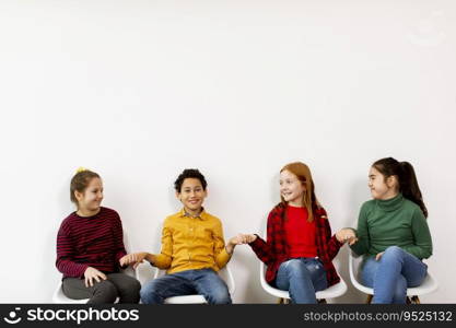 Portrait of cute little kids in jeans  sitting in chairs against the white wall