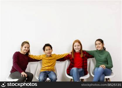 Portrait of cute little kids in jeans  sitting in chairs against the white wall