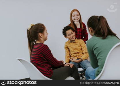 Portrait of cute little kids in jeans talking and sitting in chairs against the white wall