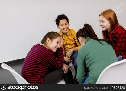 Portrait of cute little kids in jeans talking and sitting in chairs against the white wall