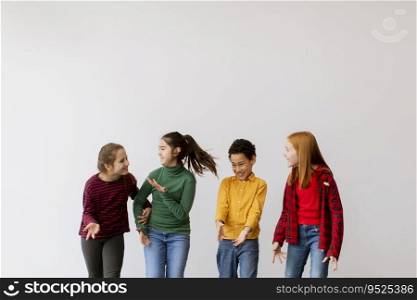 Portrait of cute little kids in jeans  talking and smiling, walking against the white wall