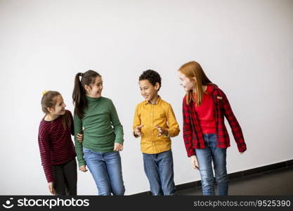 Portrait of cute little kids in jeans  talking and smiling, walking against the white wall