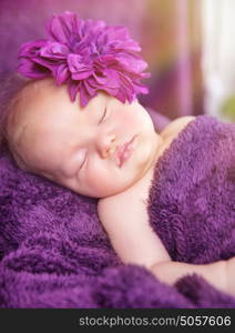 Portrait of cute little newborn girl sleeping at home, wearing stylish flower accessories, tenderness and baby fashion concept